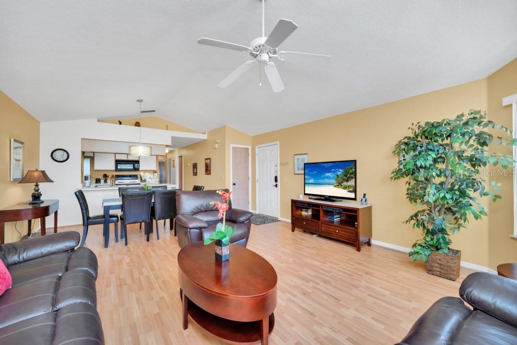 A living room with light wood flooring, a ceiling fan, and an open kitchen area — 3139 BRITANNIA BOULEVARD UNIT C, KISSIMMEE, FL