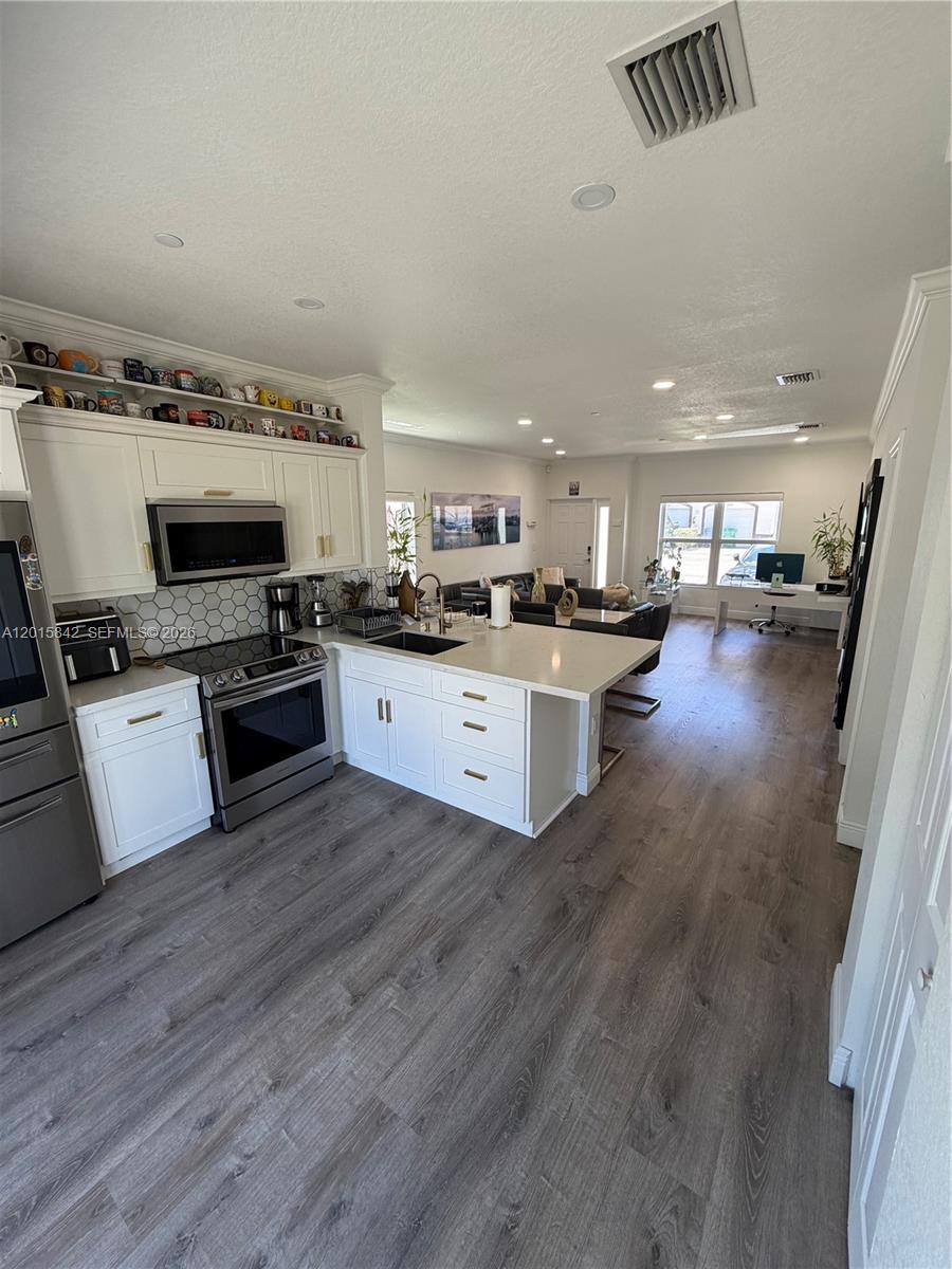 A modern kitchen with white cabinets and a quartz island opens into a living area — 2824 SW 145th Ct # 2824, Miami FL 33175, MIAMI, FL