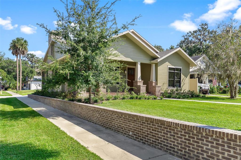 A single-story house with light green siding and a brick retaining wall along the sidewalk — 1000 S 9TH STREET, LEESBURG, FL