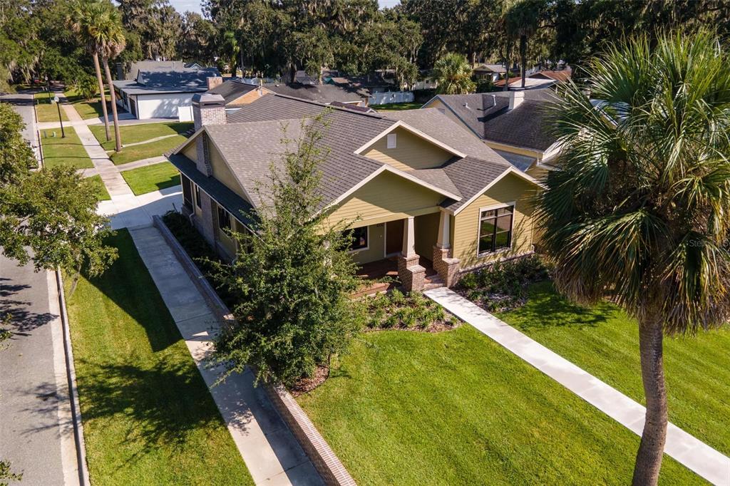 An aerial view of a tan, single-story suburban house with a dark shingled roof — 1000 S 9TH STREET, LEESBURG, FL