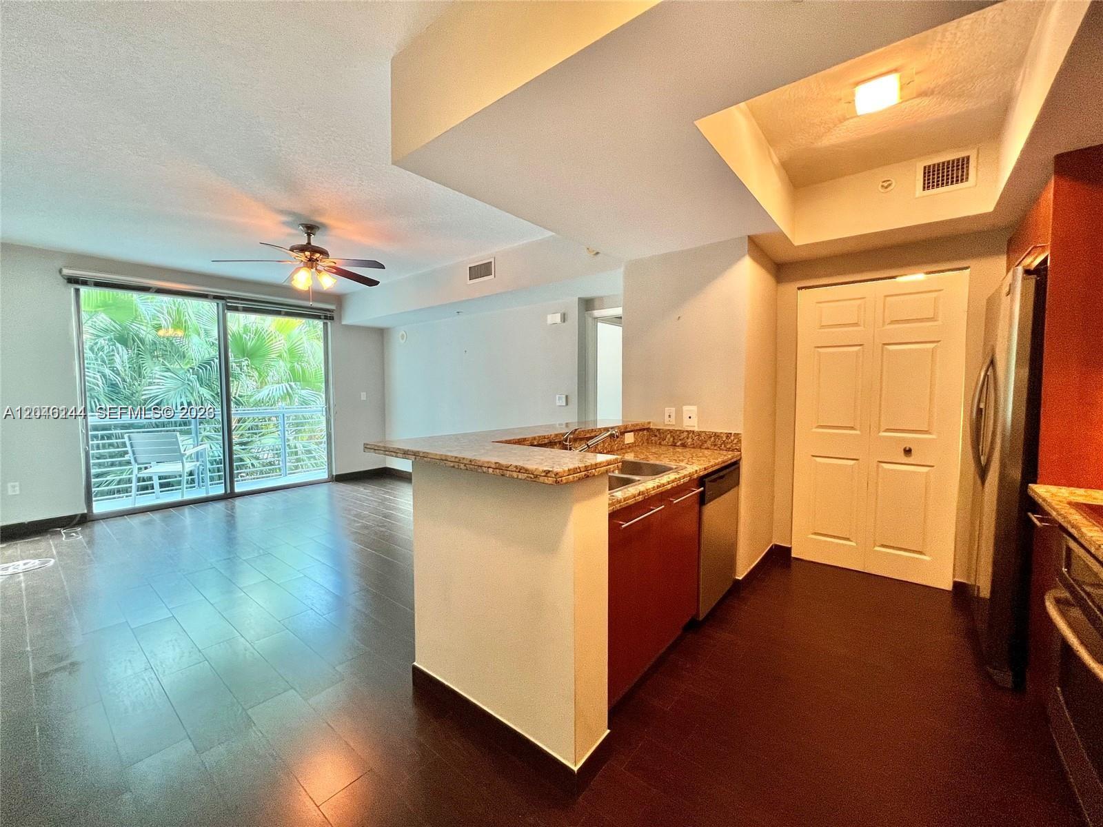 A kitchen with granite countertops and dark wood cabinets opens into a living area — 110 Washington Ave # 1506, Miami Beach FL 33139, MIAMI BEACH, FL
