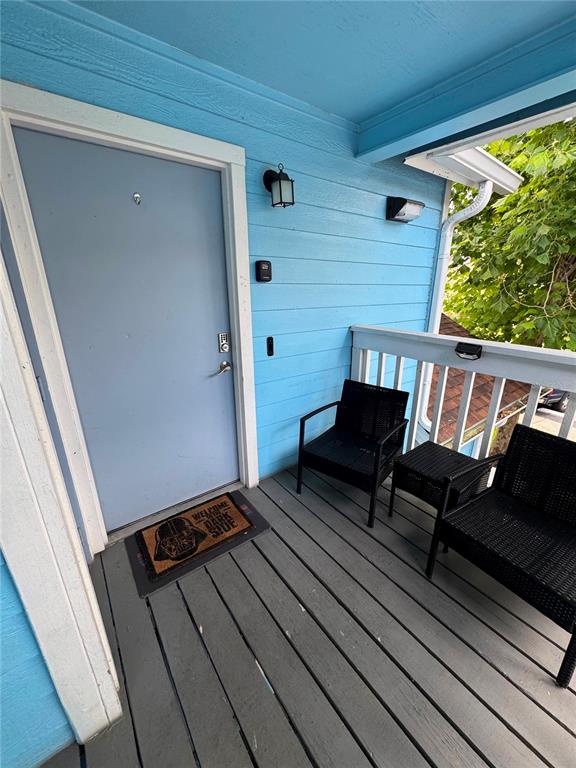 A blue-walled balcony features a gray wooden floor, two black chairs, and a Star Wars doormat — 2751 N POINCIANA BOULEVARD UNIT 30, KISSIMMEE, FL