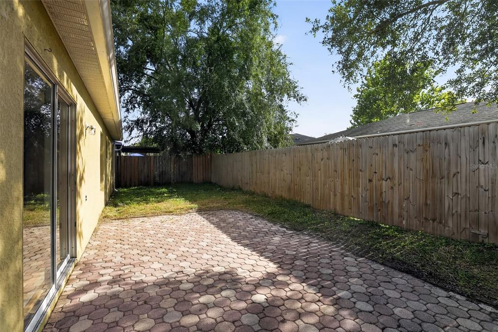A paved patio sits beside a house exterior with a wooden fence enclosing the yard — 1080 AMANDA KAY CIRCLE, SANFORD, FL