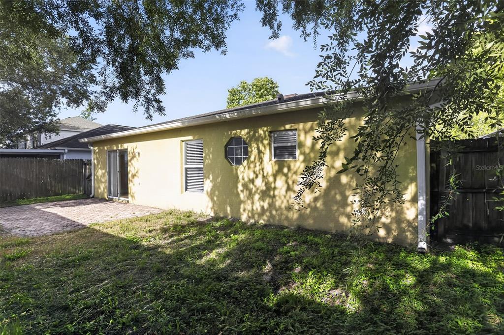 The exterior of a yellow house features a paved patio, three windows, and a wooden fence — 1080 AMANDA KAY CIRCLE, SANFORD, FL