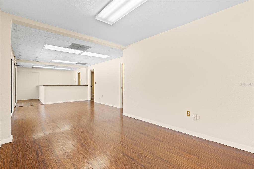 An empty office space features wood-look flooring, white walls, and a drop ceiling — 1200 S PINELLAS AVENUE, TARPON SPRINGS, FL