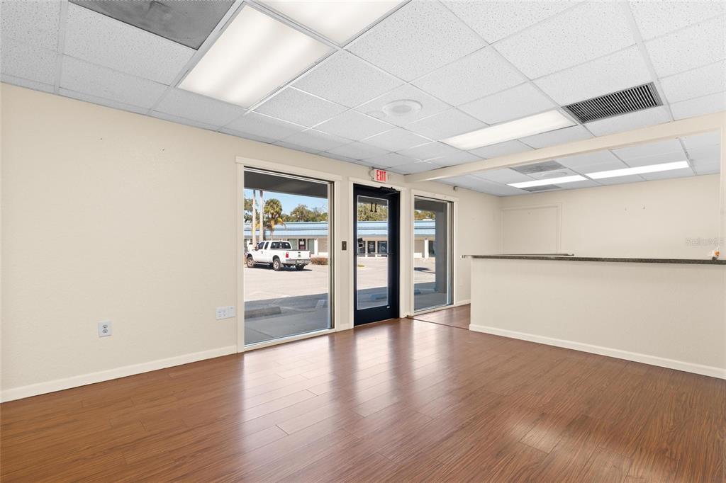 An empty commercial office space with wood-look flooring, a reception counter, and large windows — 1200 S PINELLAS AVENUE, TARPON SPRINGS, FL