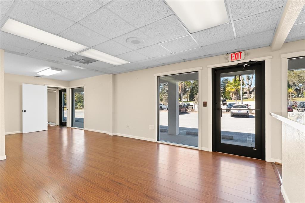 An empty office space features wood-look flooring, a drop ceiling, and glass entry doors — 1200 S PINELLAS AVENUE, TARPON SPRINGS, FL