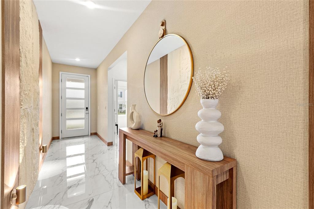 A modern entryway features a marble floor, a wooden console table, and a round mirror — 6976 ROSY SKY AVENUE, ORLANDO, FL
