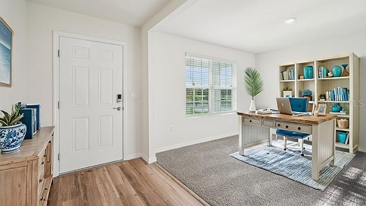 A home office features a white door, a wooden desk, a bookshelf, and carpeted flooring — 24262 NW 10TH ROAD, NEWBERRY, FL