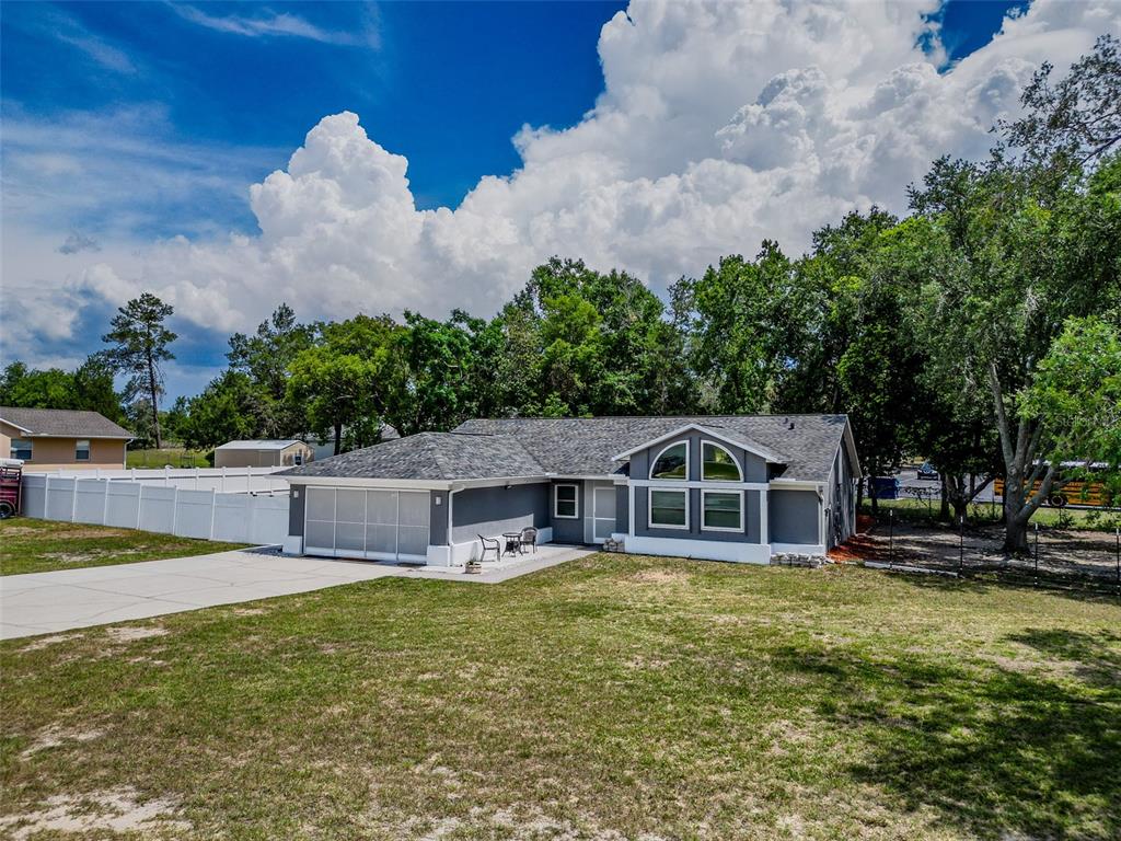 A gray single-story house with a white garage door and a large arched window — 12090 VENICE DRIVE, SPRING HILL, FL