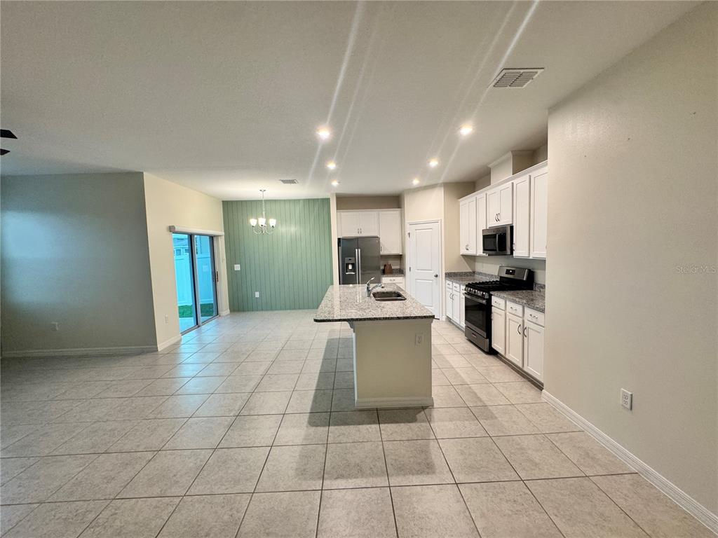A kitchen features white cabinets, granite countertops, a central island, and a green accent wall — 34100 CHIPPING SPARROW DRIVE, LEESBURG, FL