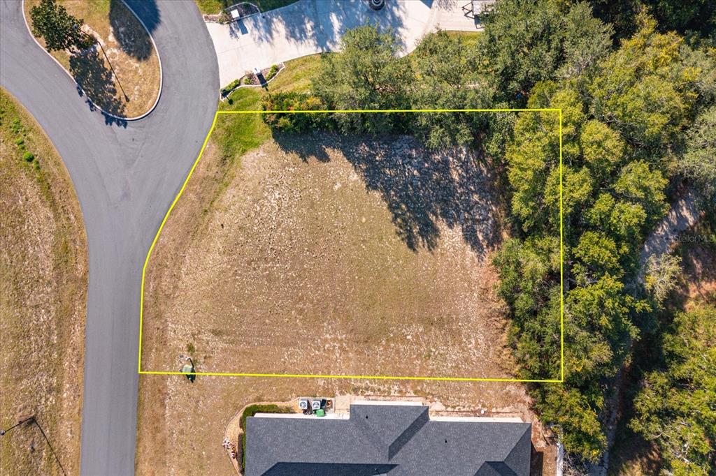 An aerial view shows a vacant, rectangular residential lot outlined in yellow next to a road — 1104 MYRTLE BREEZES COURT, FRUITLAND PARK, FL