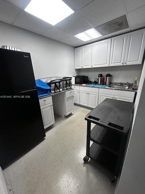A small kitchen features white cabinets, a black refrigerator, and a black utility cart — 900 W 49th St Suite B001, Hialeah FL 33012, HIALEAH, FL