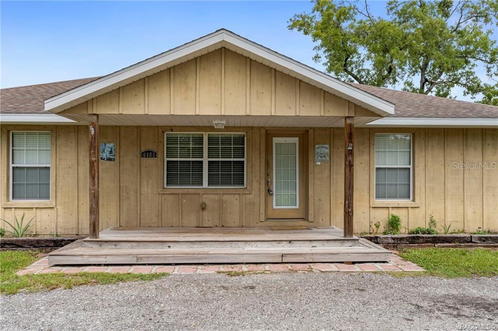 A single-story house with tan vertical siding, a front porch, and a gravel driveway — 6185 W OST WEST STREET, HOMOSASSA, FL