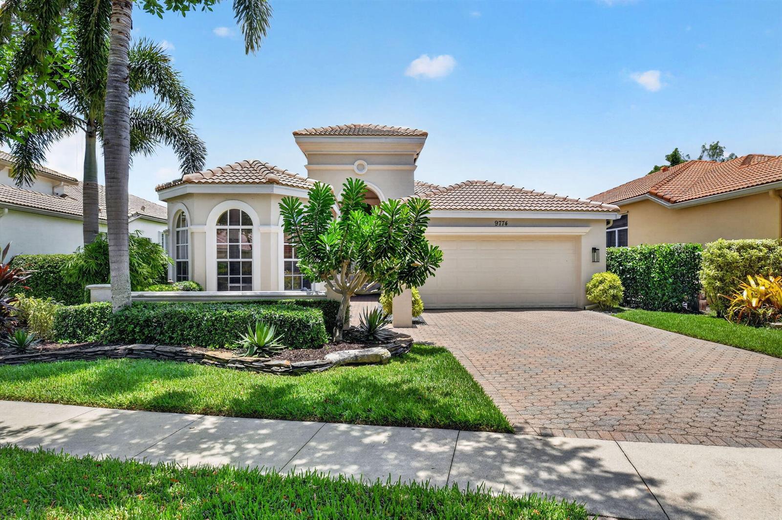 A single-story stucco house with a tile roof, arched windows, and a paved driveway — 9774 Via Elegante, Wellington FL 33411, WELLINGTON, FL