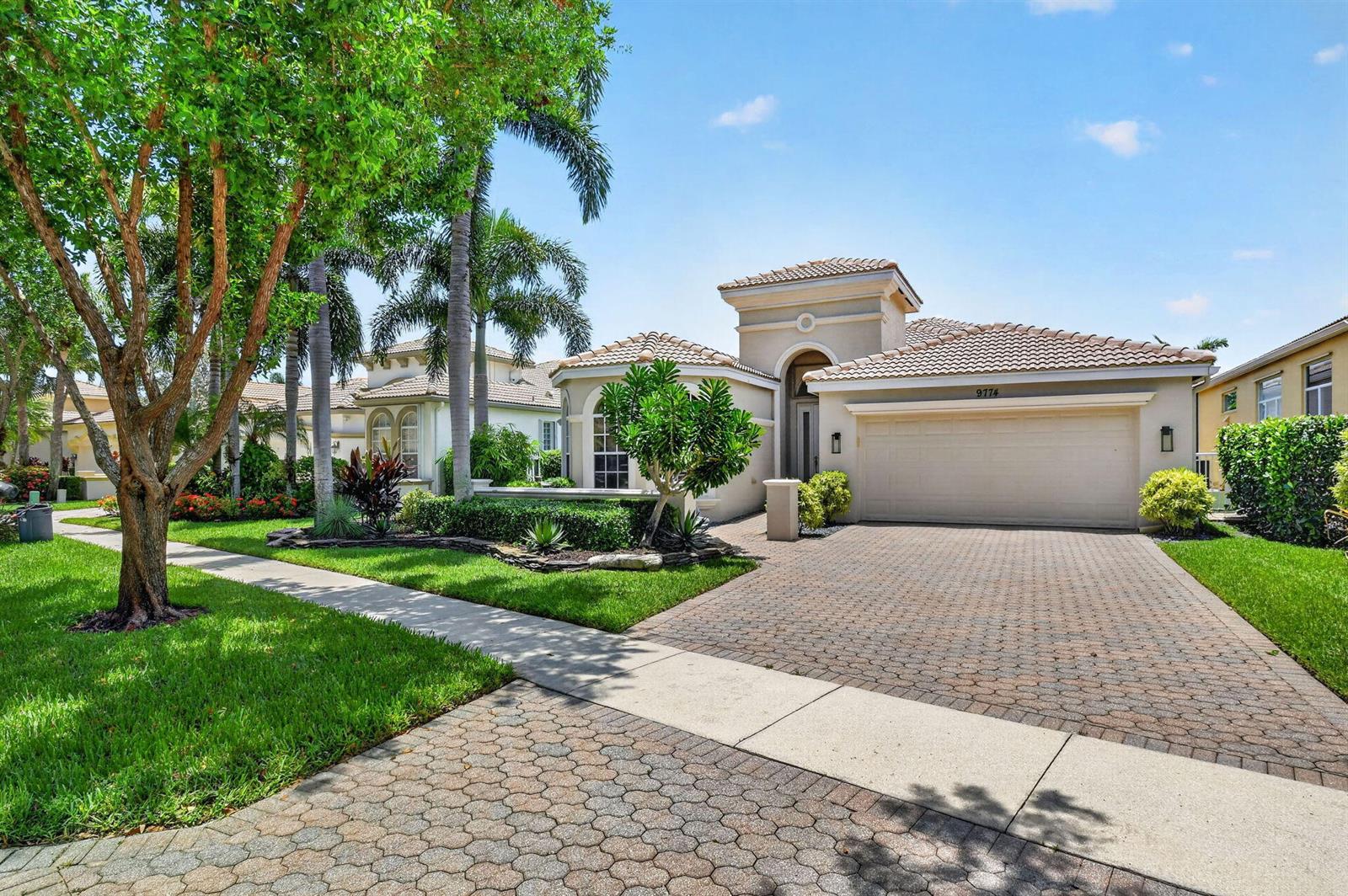A single-story suburban house with a tiled roof, a two-car garage, and a paved driveway — 9774 Via Elegante, Wellington FL 33411, WELLINGTON, FL