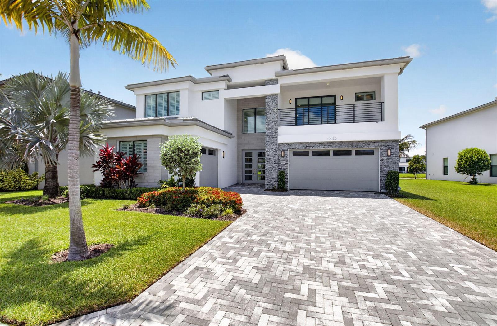 A two-story modern house features a stone facade, a paved driveway, and a balcony — 17089 Rainbow Falls Trail, Boca Raton FL 33496, BOCA RATON, FL