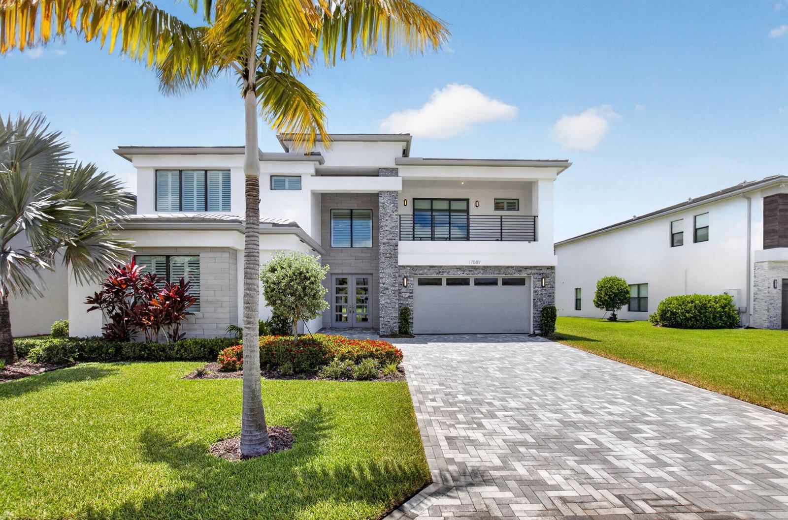 A modern two-story house features a stone facade, a balcony, and a paved driveway — 17089 Rainbow Falls Trail, Boca Raton FL 33496, BOCA RATON, FL