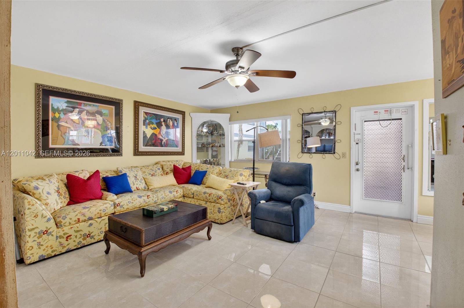 A living room features a floral sectional sofa, a blue recliner, and light tile flooring — 537 Brittany L # 537, Delray Beach FL 33446, DELRAY BEACH, FL
