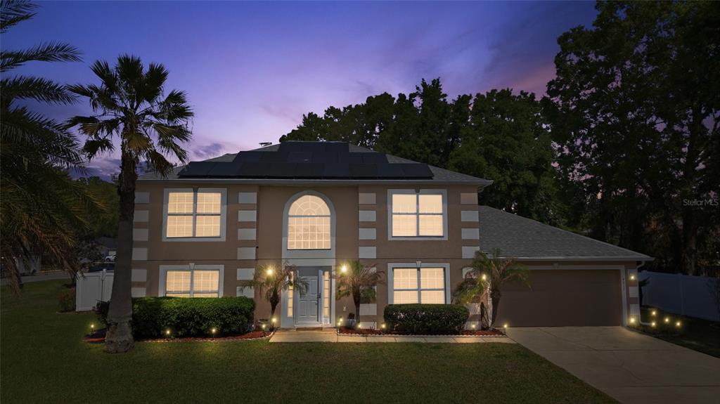 A two-story house with a tan exterior, solar panels, and a front-facing garage at dusk — 4517 SE 28TH STREET, OCALA, FL