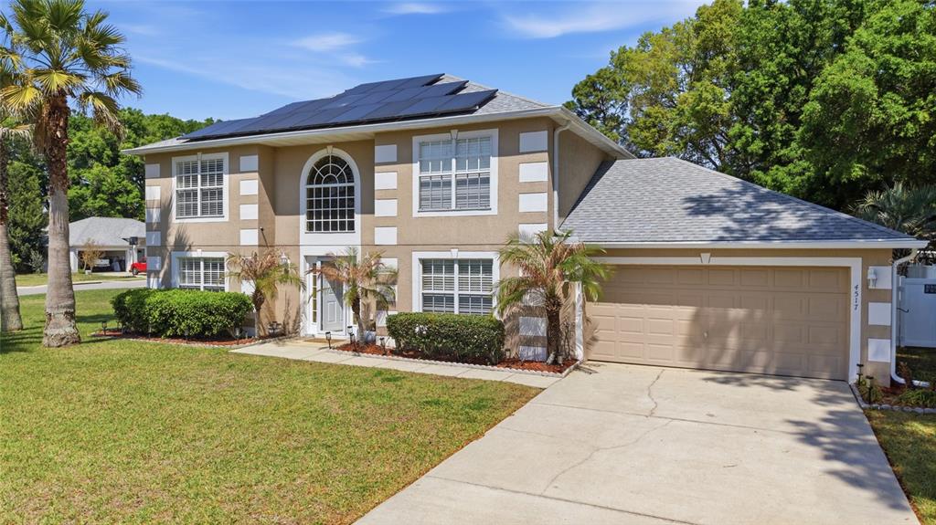 A two-story house with a tan stucco exterior, white trim, and solar panels on the roof — 4517 SE 28TH STREET, OCALA, FL