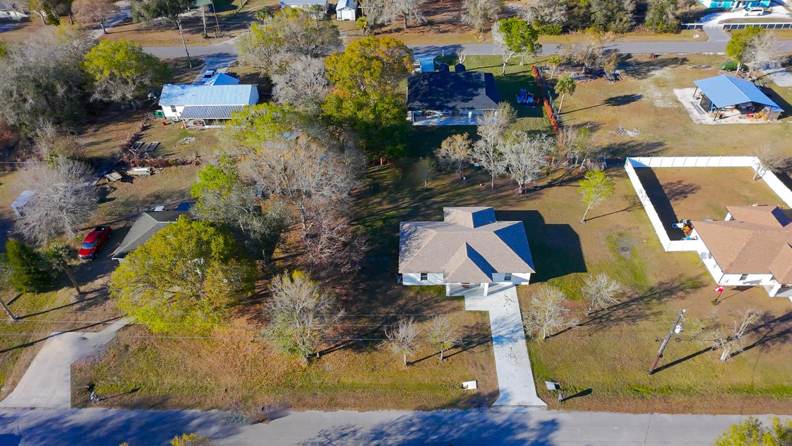 An aerial view shows several houses with driveways, trees, and yards in a residential neighborhood — 7757 NW 82nd Court, Okeechobee FL 34972, OKEECHOBEE, FL