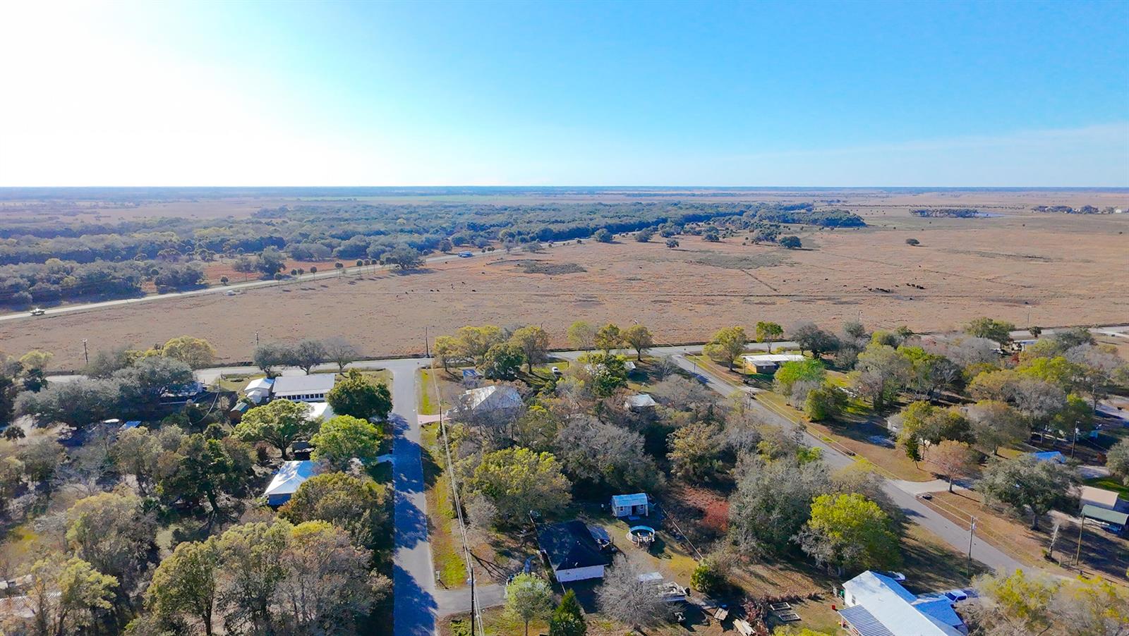 An aerial view shows a rural neighborhood with scattered houses surrounded by trees and fields — 7757 NW 82nd Court, Okeechobee FL 34972, OKEECHOBEE, FL