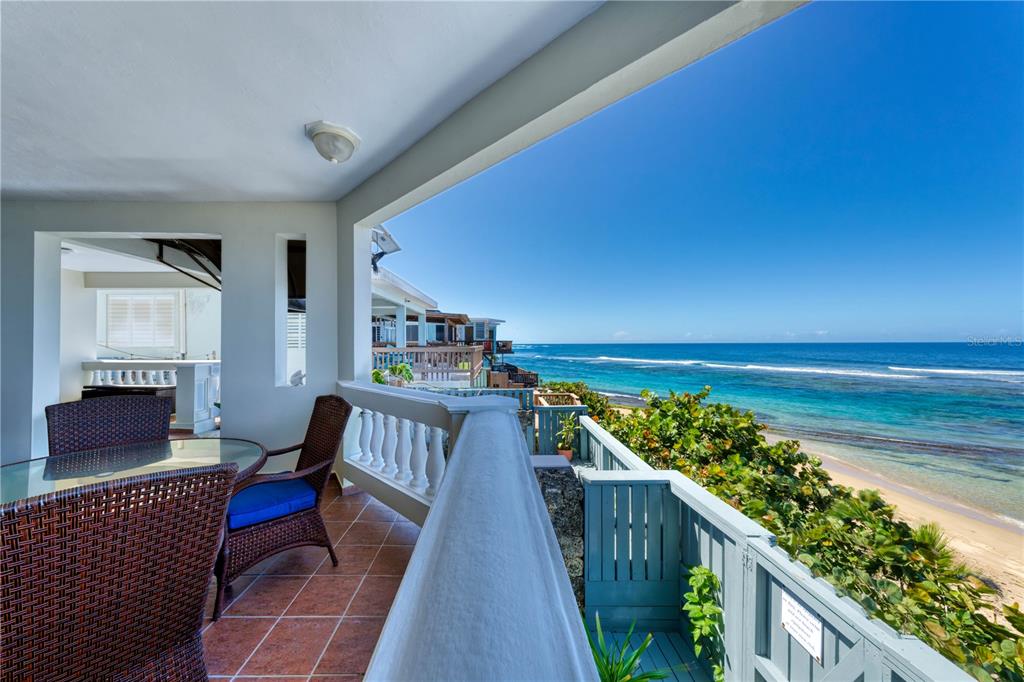 A covered balcony with outdoor furniture overlooks a sandy beach and the ocean — Carr. 466 K5 H3, ISABELA, PR