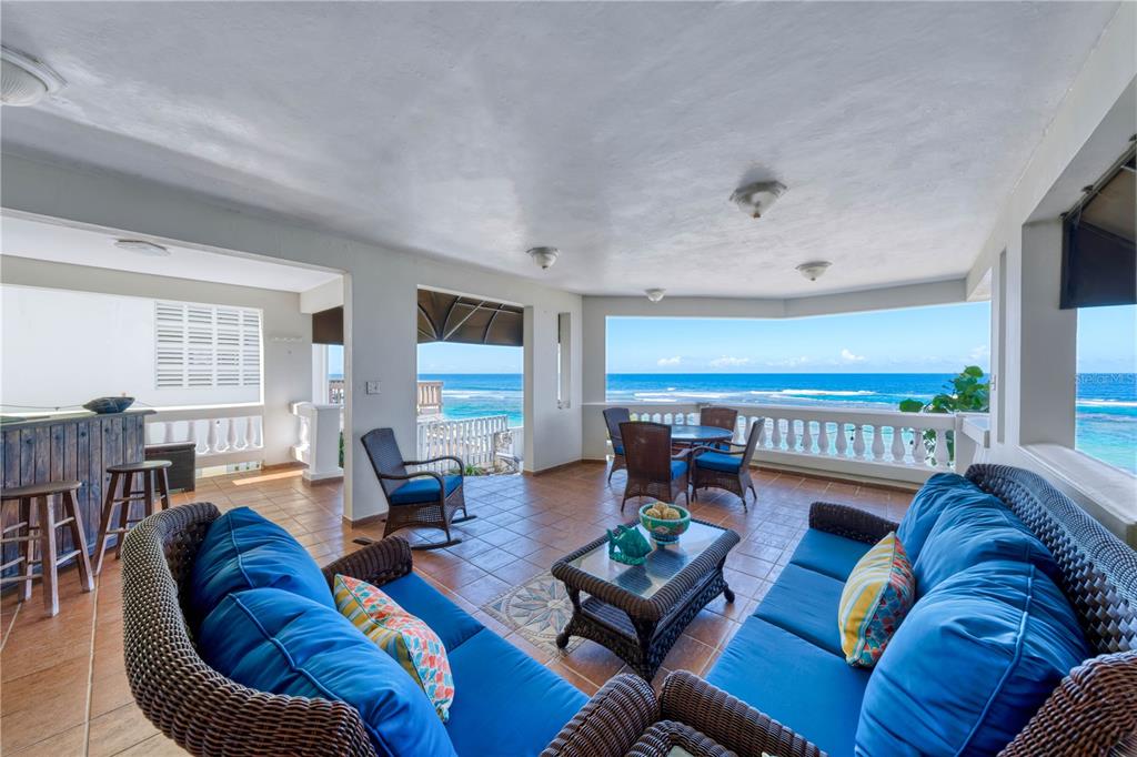 An open-air patio with wicker furniture overlooks the ocean from a tiled balcony — Carr. 466 K5 H3, ISABELA, PR