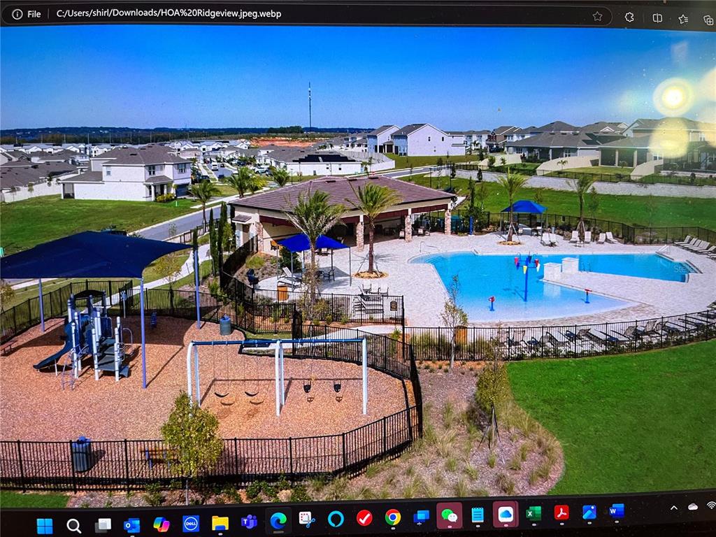 An aerial view shows a community swimming pool and playground surrounded by residential homes — 7757 MARSALA STREET, CLERMONT, FL