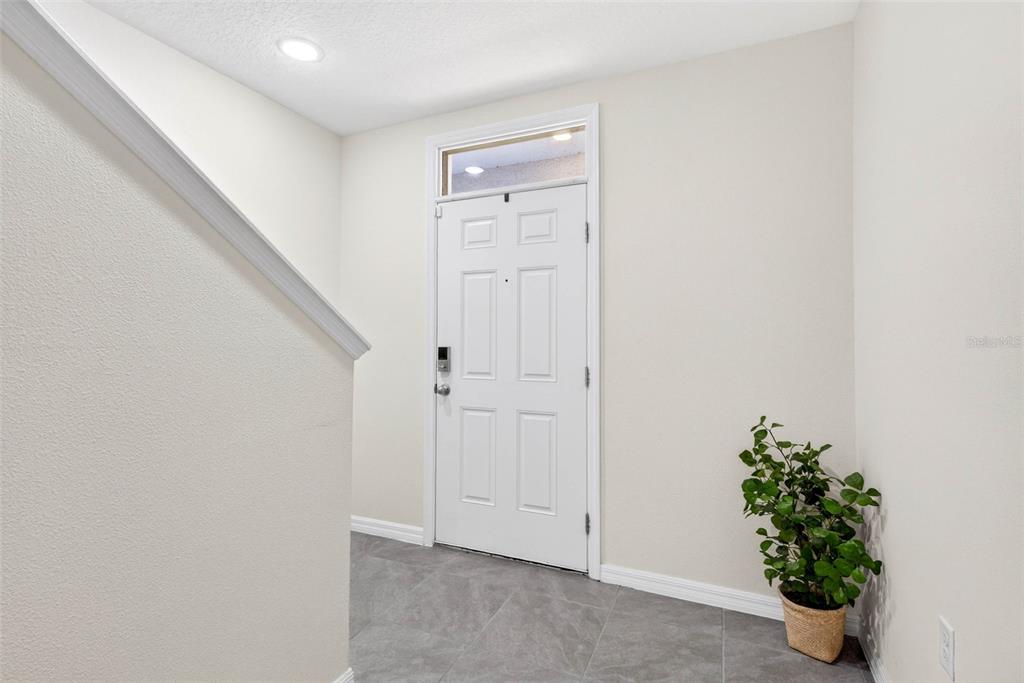 An entryway features a white door with a transom window, gray tile flooring, and stairs — 35686 SUNFLOWER HILL DRIVE, ZEPHYRHILLS, FL