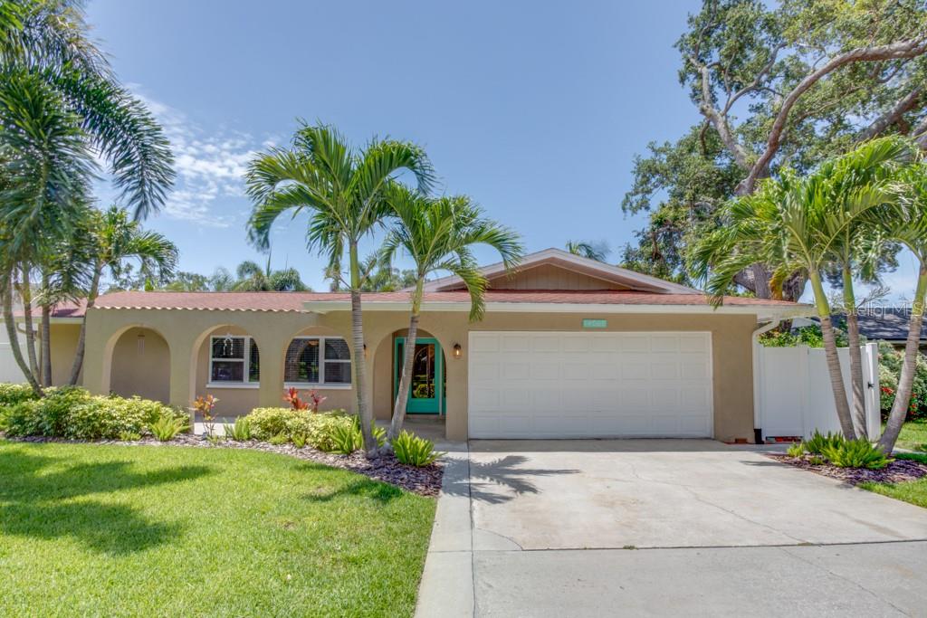 A single-story house with a white garage door, tan stucco exterior, and palm trees — 14060 82ND AVENUE, SEMINOLE, FL