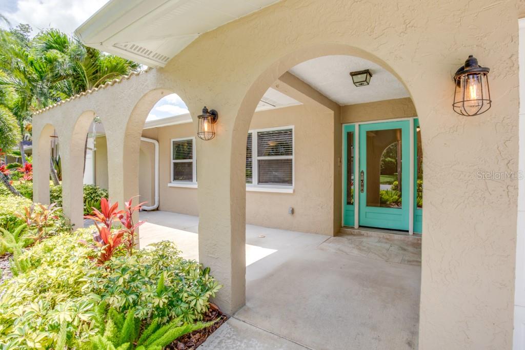 A covered entryway features arched stucco columns, a turquoise front door, and outdoor wall lanterns — 14060 82ND AVENUE, SEMINOLE, FL