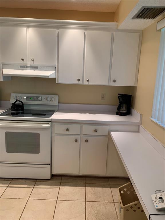 A kitchen features white cabinets, white appliances, a tiled floor, and a white countertop — 1717 PELICAN COVE ROAD UNIT 333, SARASOTA, FL