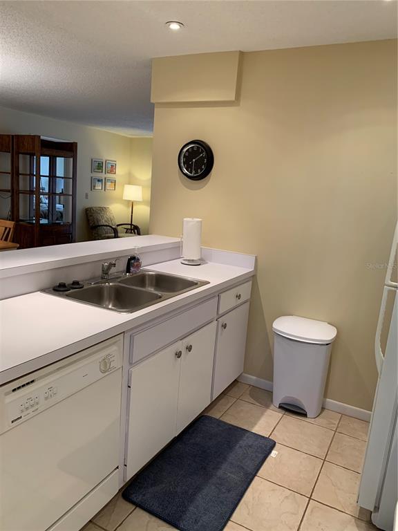 A kitchen features white cabinets, a double-basin sink, a dishwasher, and a white trash can — 1717 PELICAN COVE ROAD UNIT 333, SARASOTA, FL