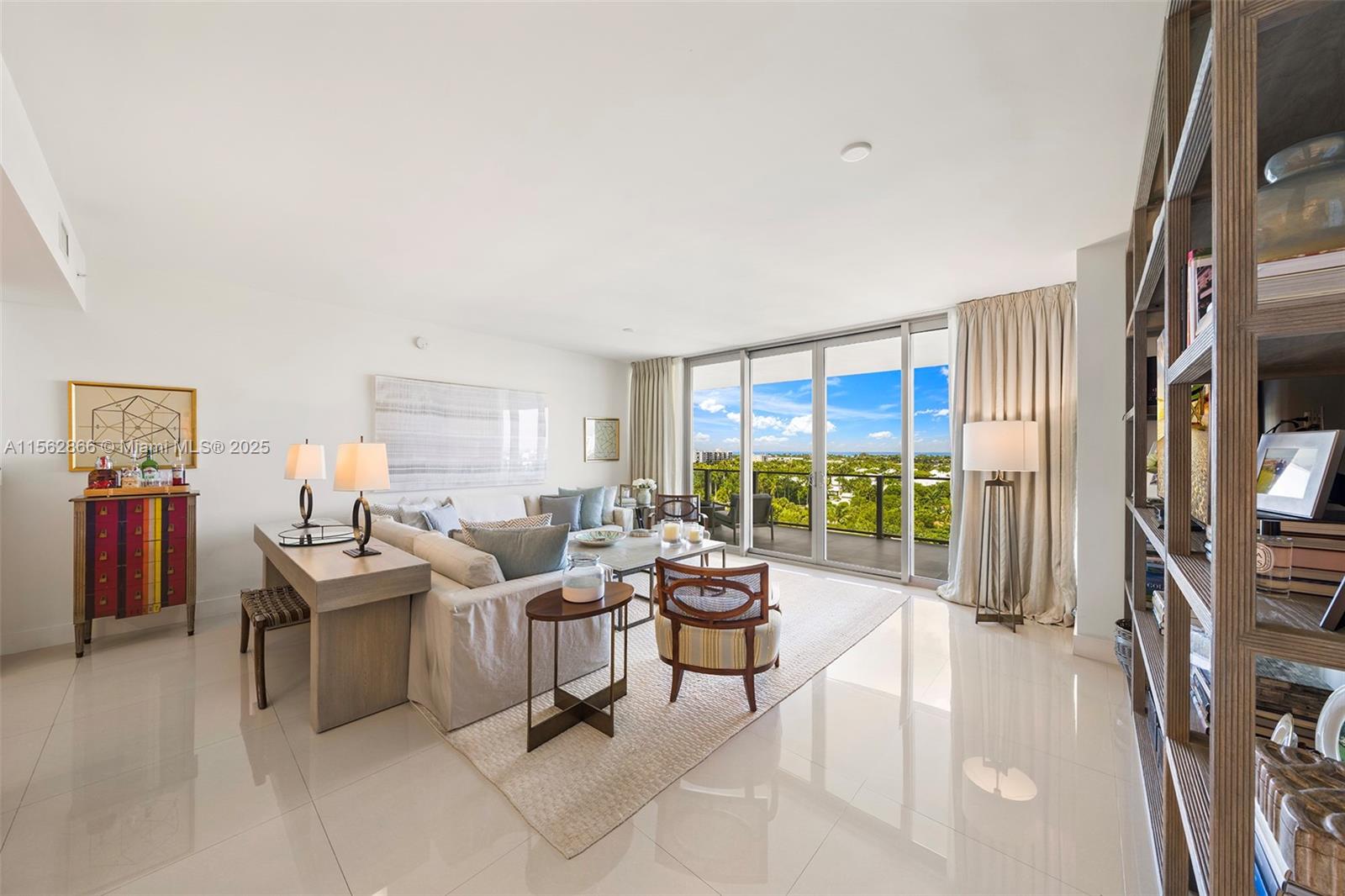 A bright living room features a sofa, a bookshelf, and a balcony with outdoor views — 360 Ocean Dr # 905S, Key Biscayne FL 33149, KEY BISCAYNE, FL