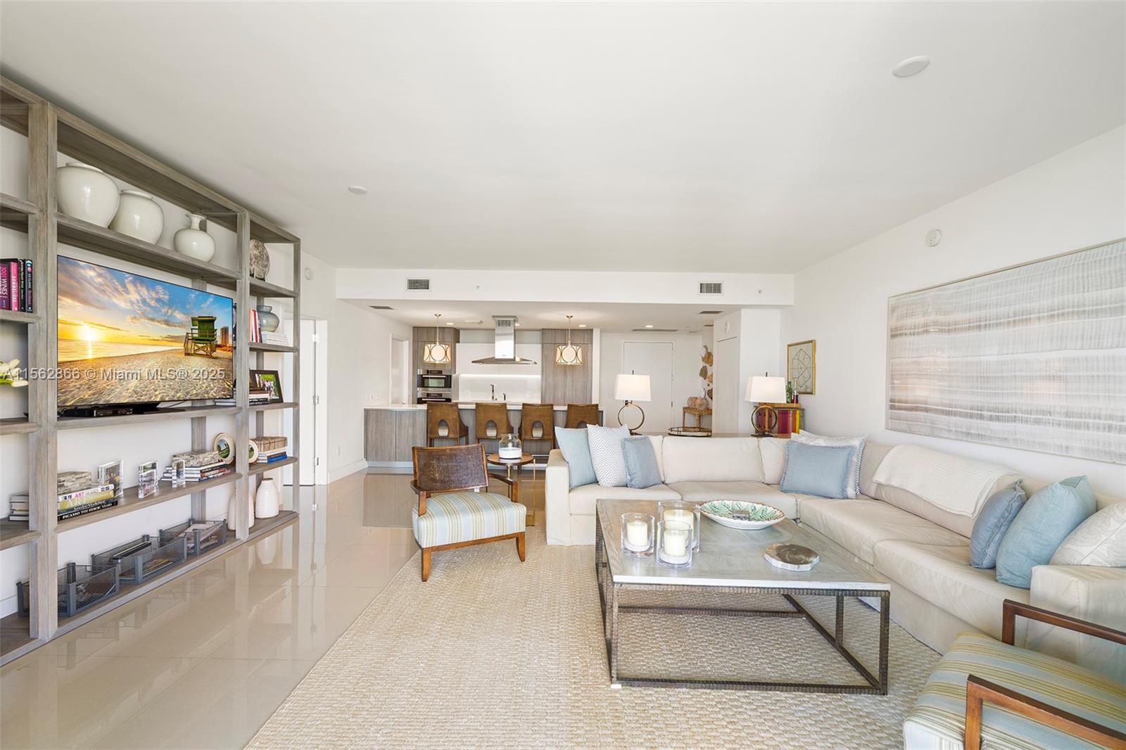 A modern living room features a large sectional sofa, a television unit, and an open kitchen — 360 Ocean Dr # 905S, Key Biscayne FL 33149, KEY BISCAYNE, FL