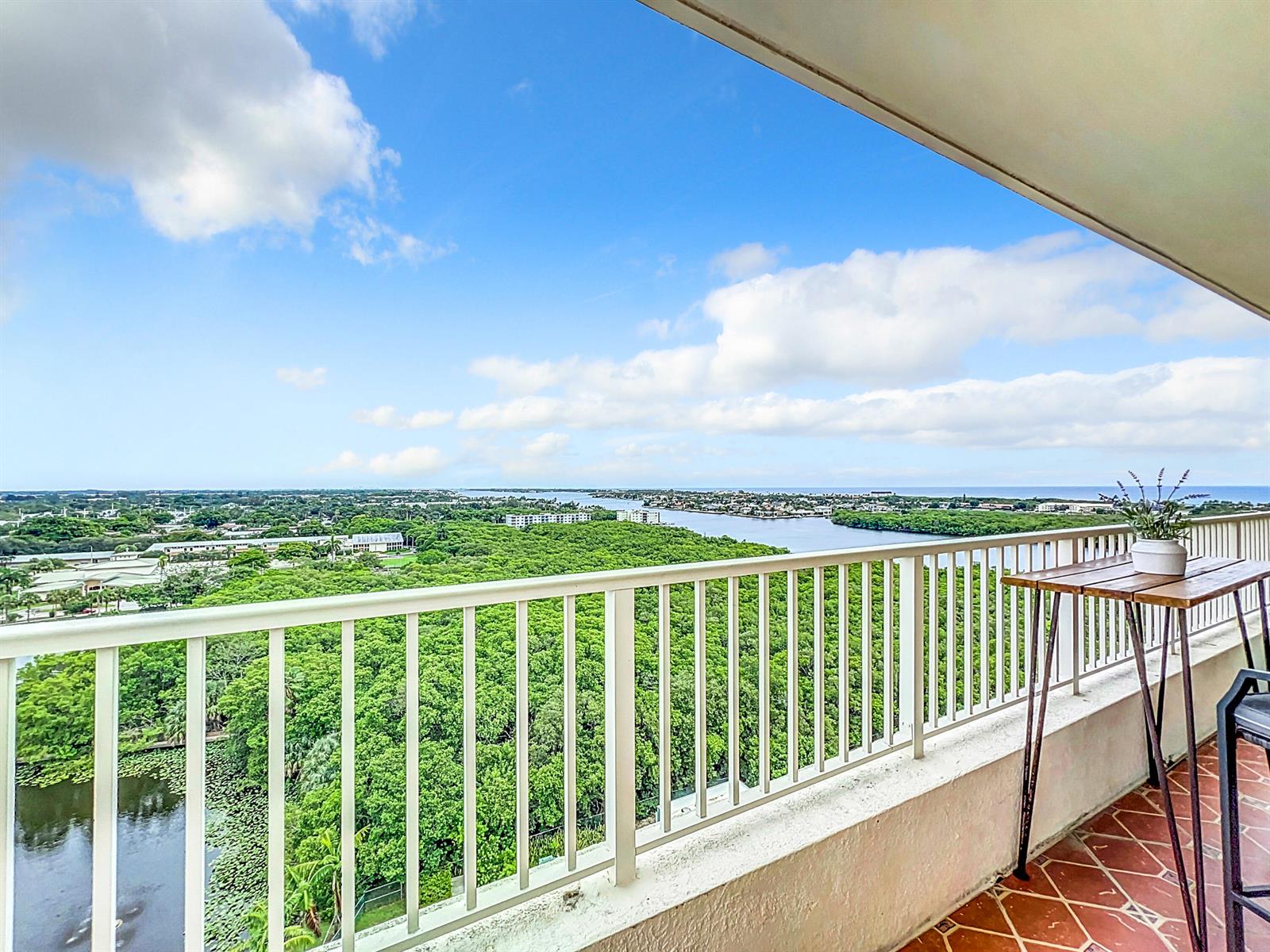 A high-rise balcony with a white railing overlooks a dense forest and a distant waterway — 700 E Boynton Beach Boulevard # 1408, Boynton Beach FL 33435, BOYNTON BEACH, FL