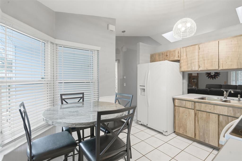 A kitchen with light wood cabinets, a white refrigerator, and a small round dining table — 61 FLORIDANA ROAD, DEBARY, FL
