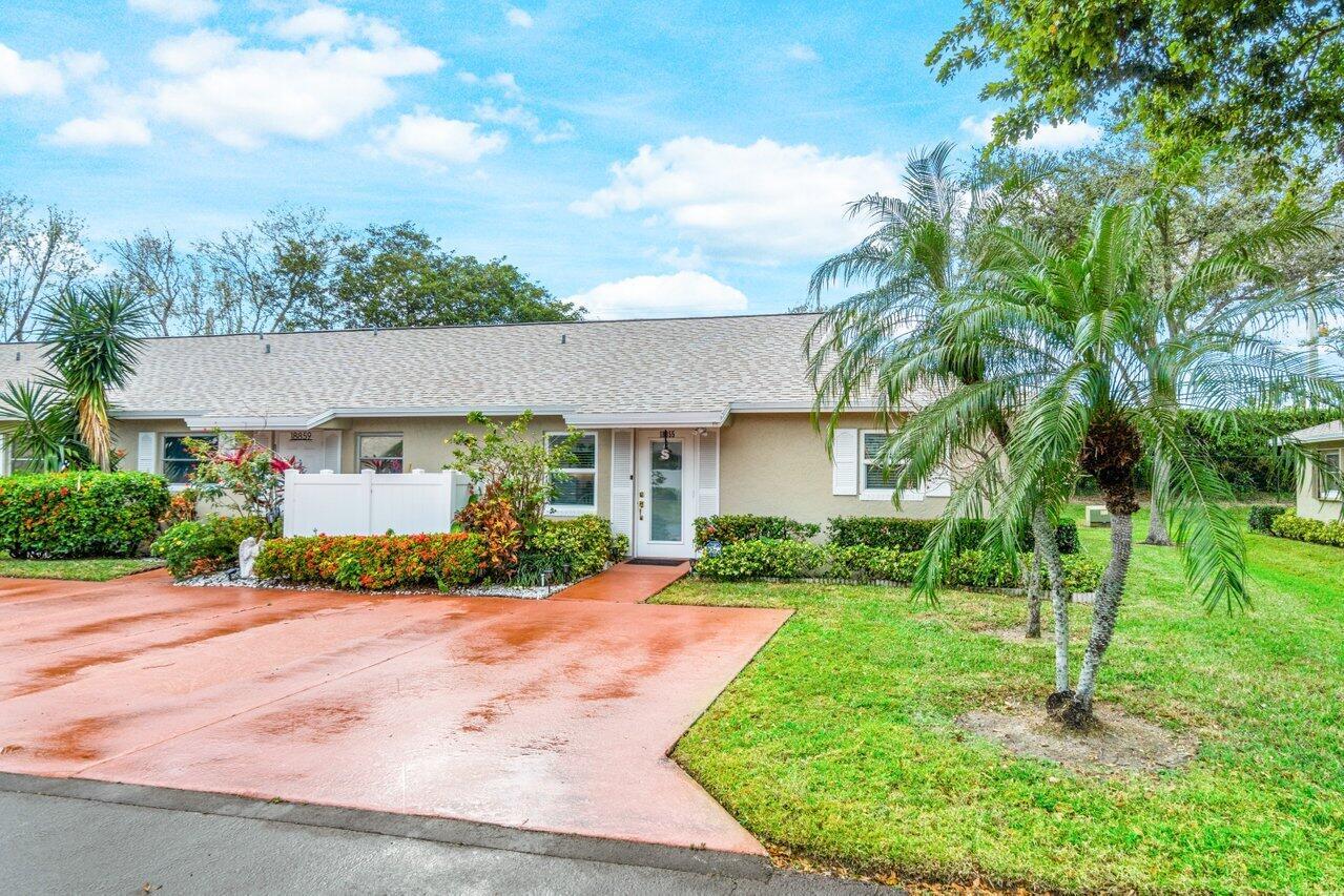 A single-story duplex with a red concrete driveway, palm trees, and white privacy fencing — 18855 Candlewick Drive, Boca Raton FL 33496, BOCA RATON, FL