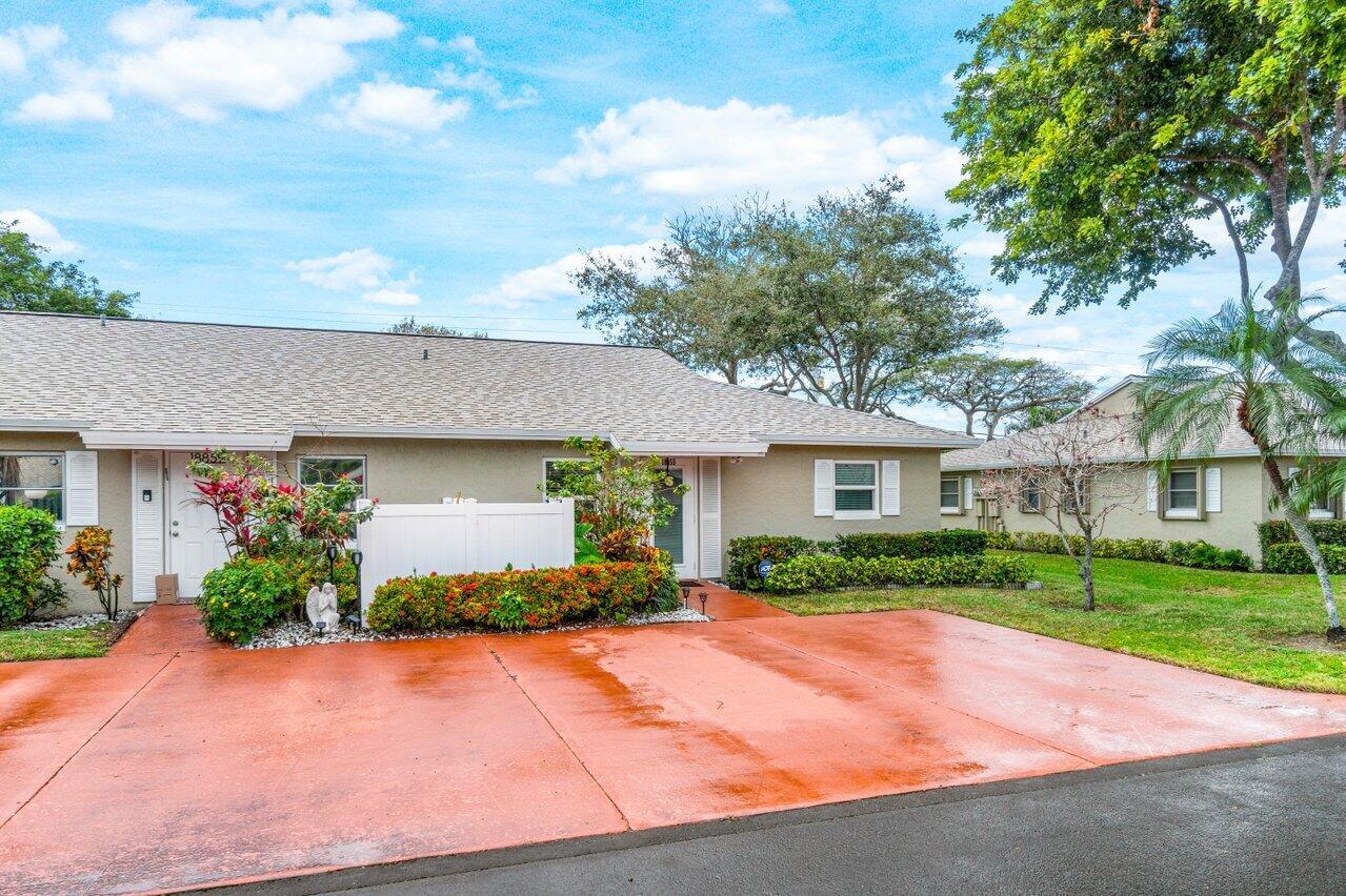 A single-story duplex with a red concrete driveway, white privacy fence, and landscaped front yard — 18855 Candlewick Drive, Boca Raton FL 33496, BOCA RATON, FL
