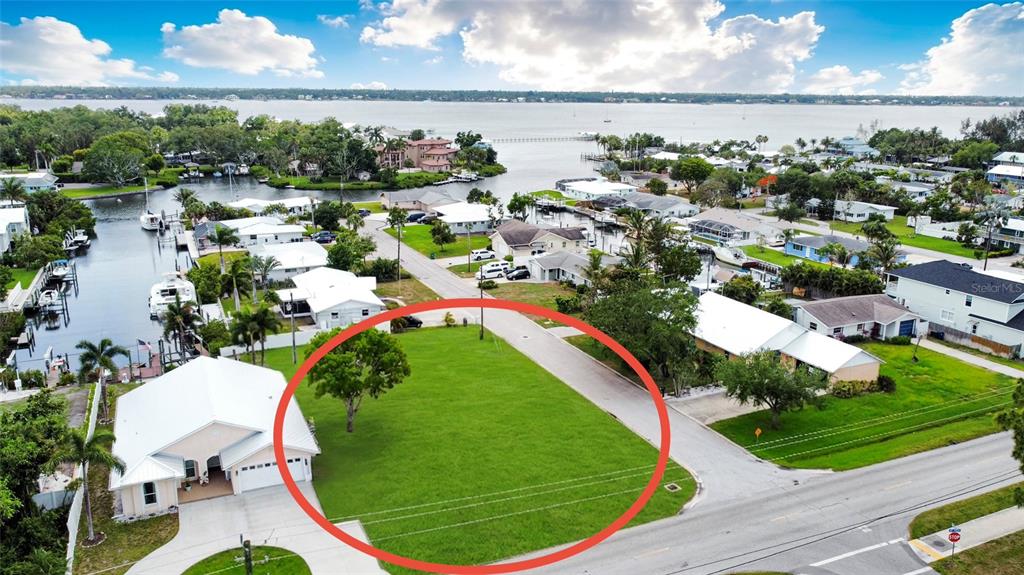 An aerial view shows a vacant, grassy residential lot situated near a waterfront neighborhood — 2213 10TH STREET W, PALMETTO, FL