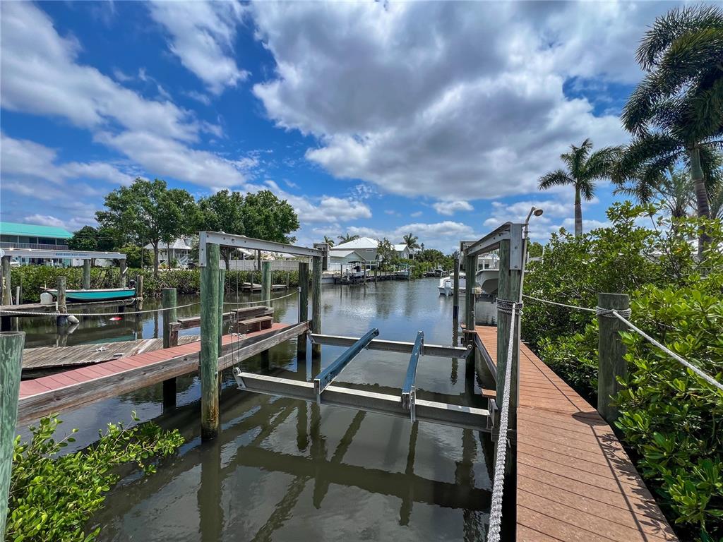A boat lift sits between two wooden docks on a canal lined with mangroves — 2213 10TH STREET W, PALMETTO, FL
