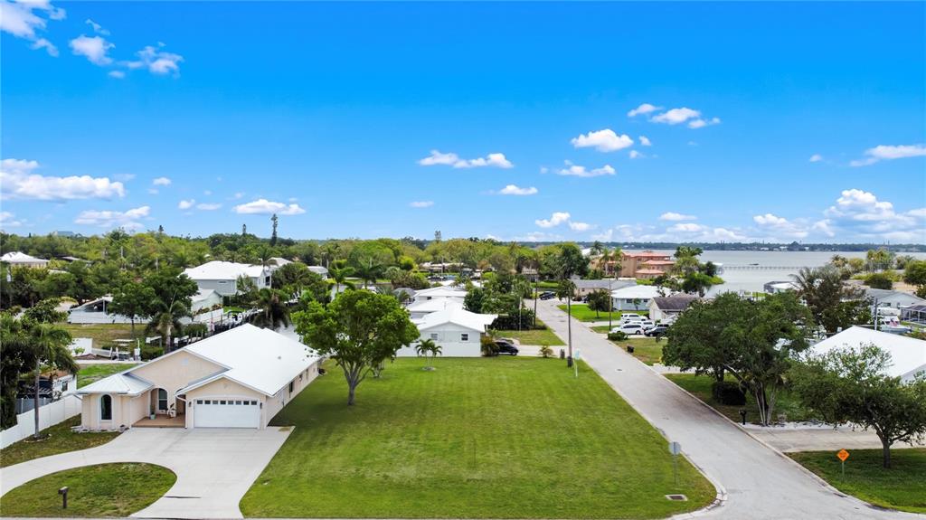 An aerial view shows a residential street with a large grassy lot and nearby houses — 2213 10TH STREET W, PALMETTO, FL