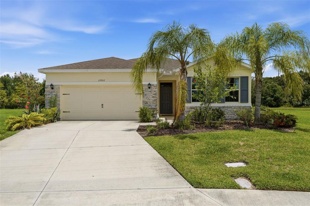 A single-story house with a beige stucco exterior, stone accents, and a two-car garage — 13922 WOODBRIDGE TERRACE, BRADENTON, FL