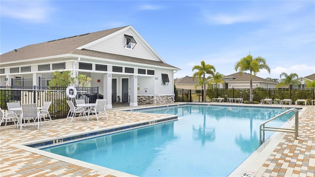 A swimming pool with a patio area sits in front of a community clubhouse building — 13922 WOODBRIDGE TERRACE, BRADENTON, FL