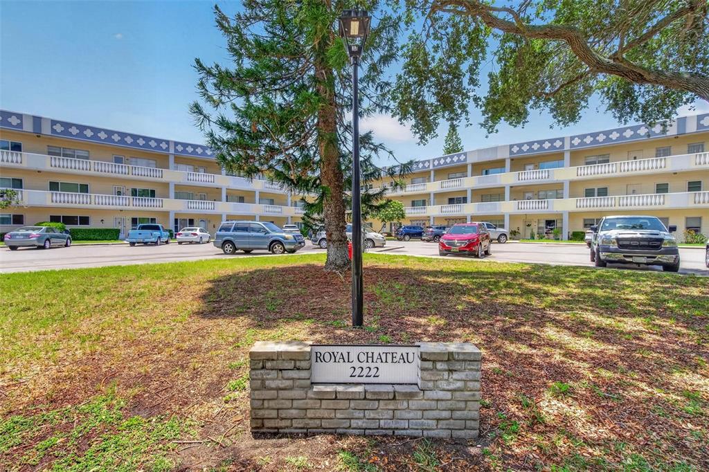 A brick sign for Royal Chateau stands in front of a multi-story apartment complex — 2222 AMERICUS BOULEVARD N UNIT 18, CLEARWATER, FL