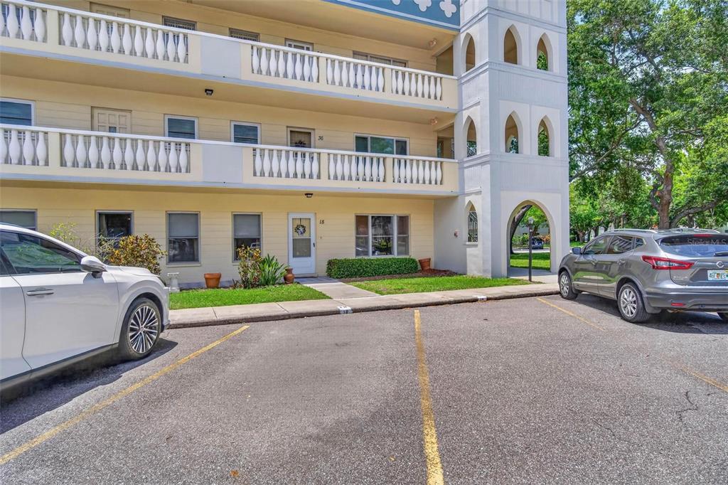 A three-story apartment building exterior with balconies and a parking lot in the foreground — 2222 AMERICUS BOULEVARD N UNIT 18, CLEARWATER, FL