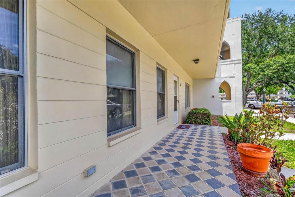 A covered outdoor walkway features a diamond-patterned tile floor and light-colored horizontal siding — 2222 AMERICUS BOULEVARD N UNIT 18, CLEARWATER, FL