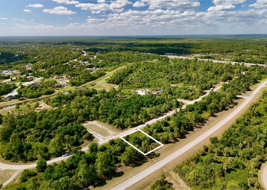 An aerial view shows a vacant, wooded rectangular lot outlined in white along a road — CUSTER CIRCLE, NORTH PORT, FL